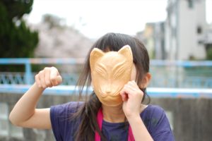 a girl with a fox face rice cracker which is popular at Fushimi Inari Taisha